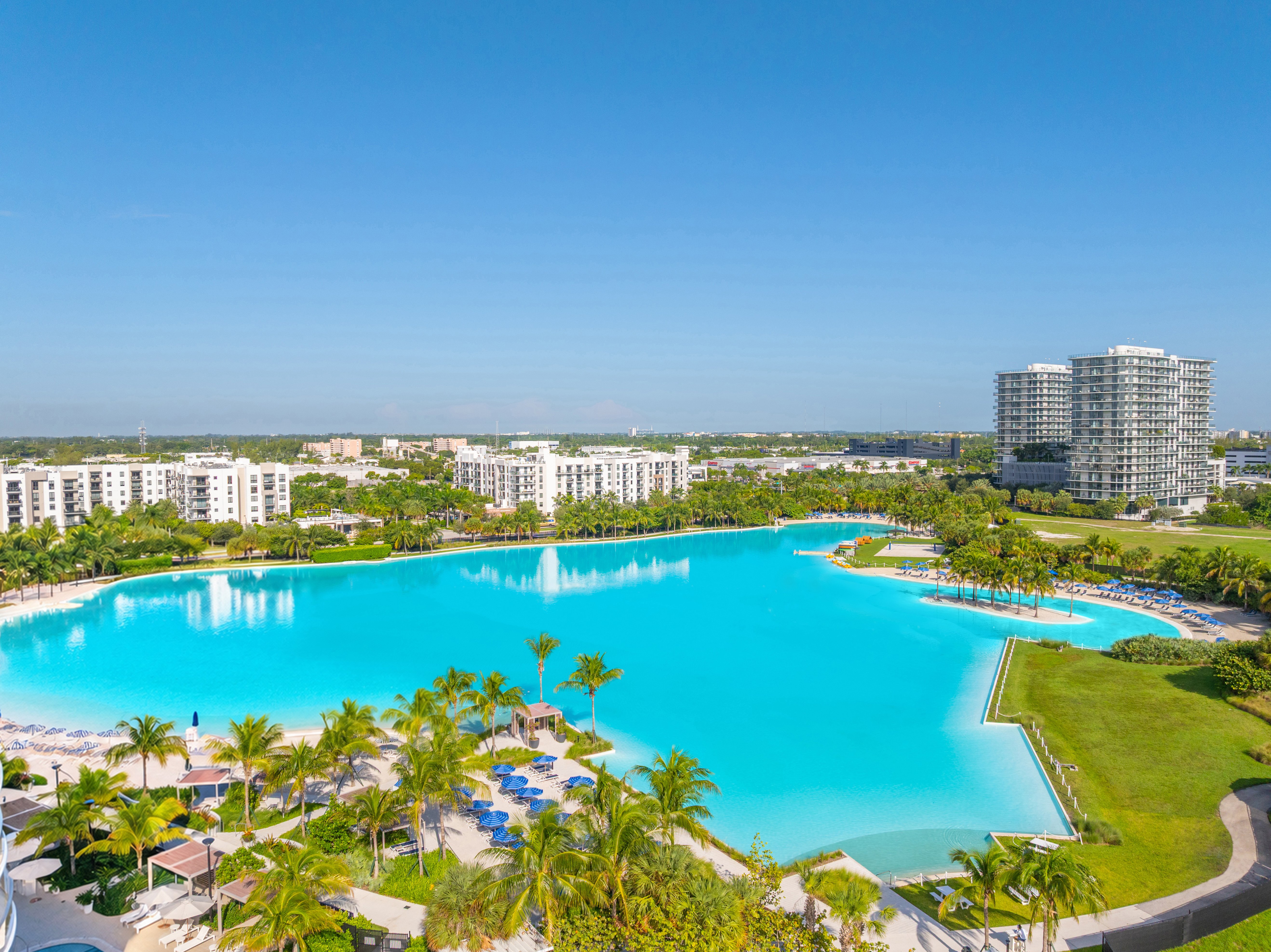 A large swimming pool surrounded by palm trees and a resort.